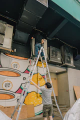 two men painting a mural on the side of a building