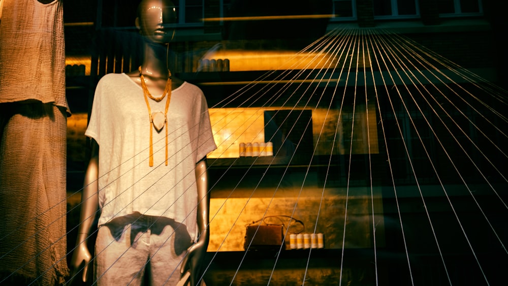a mannequin wearing a white shirt and necklace