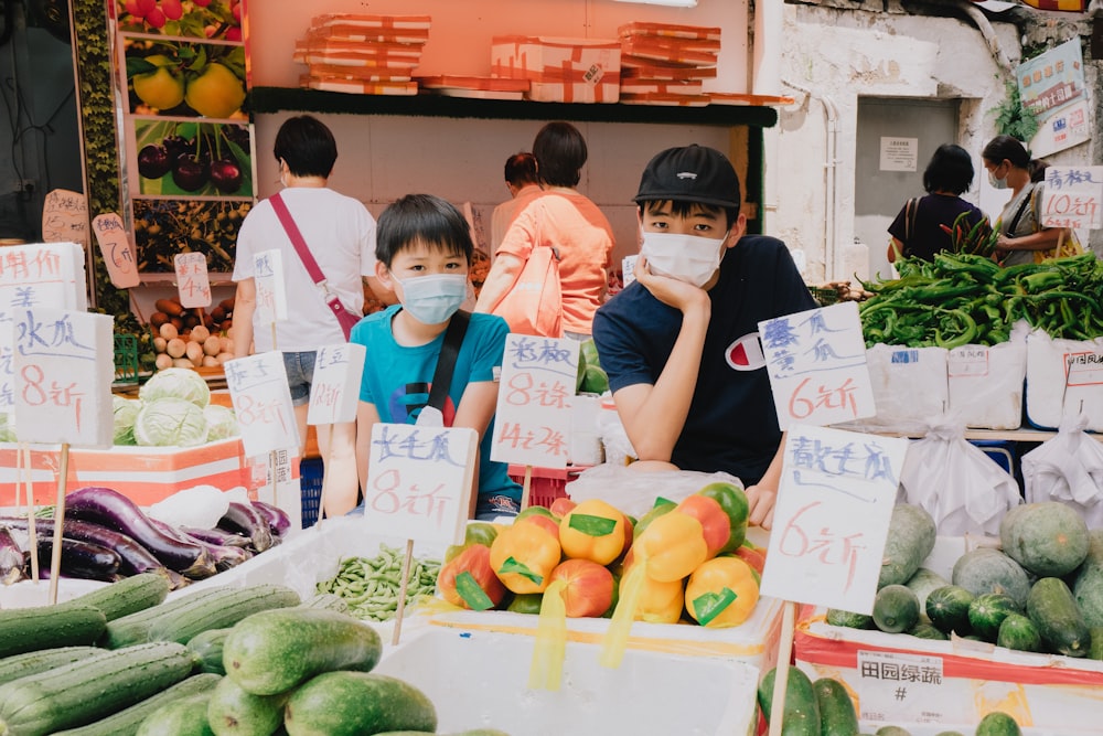 a group of people standing in front of a fruit and vegetable stand