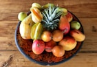 a bowl filled with fruit on top of a wooden table