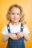a little girl in overalls posing for a picture