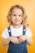 a little girl in overalls posing for a picture
