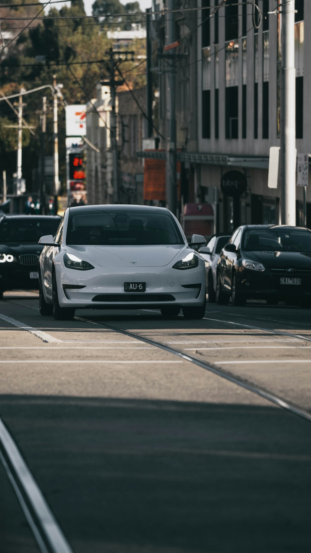 a white car driving down a street next to tall buildings