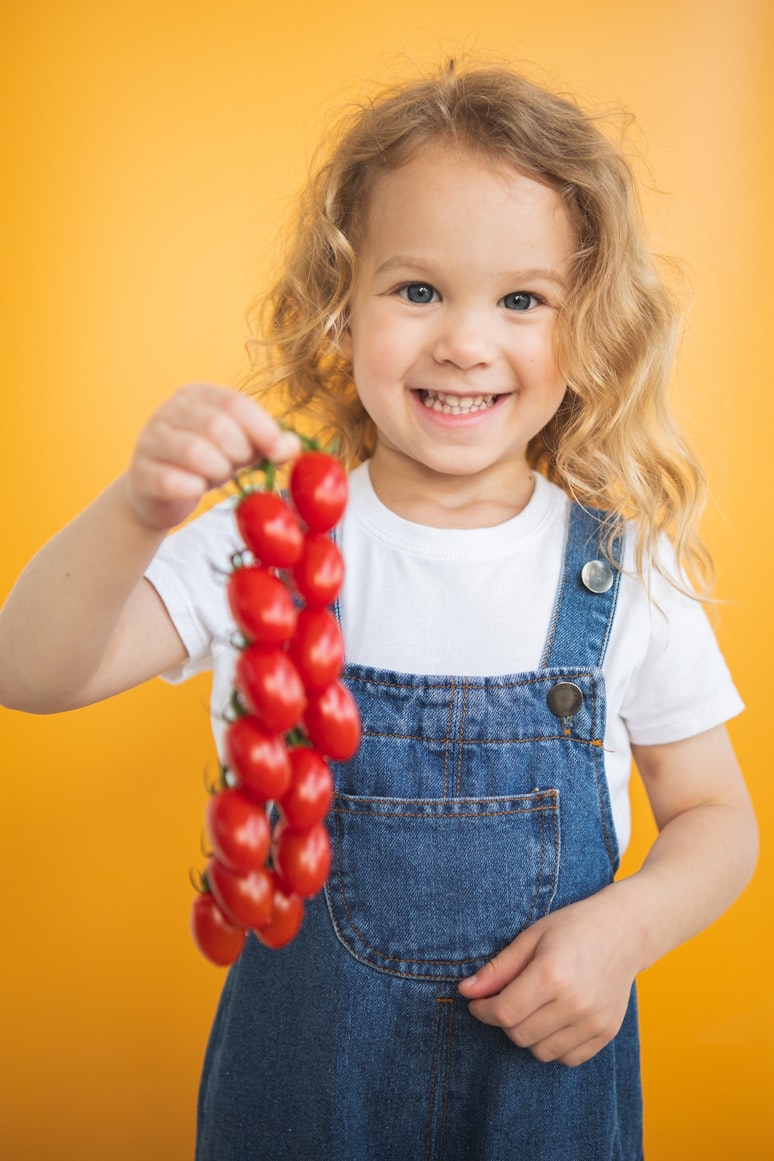 Little girl holding fresh tomatoes from the garden
