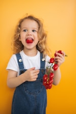 a little girl holding a bunch of tomatoes