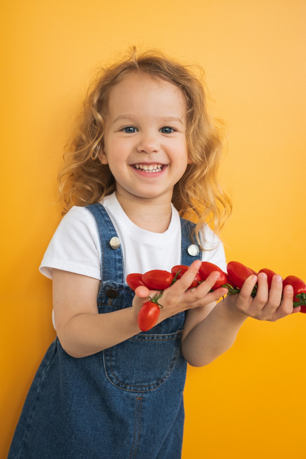 a little girl holding a bunch of tomatoes