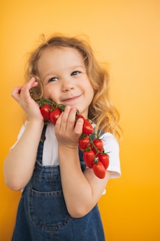 a little girl holding a bunch of tomatoes