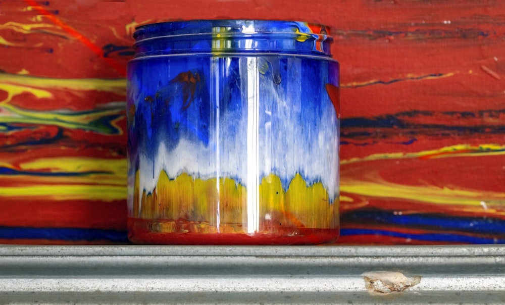 a blue and yellow vase sitting on top of a shelf