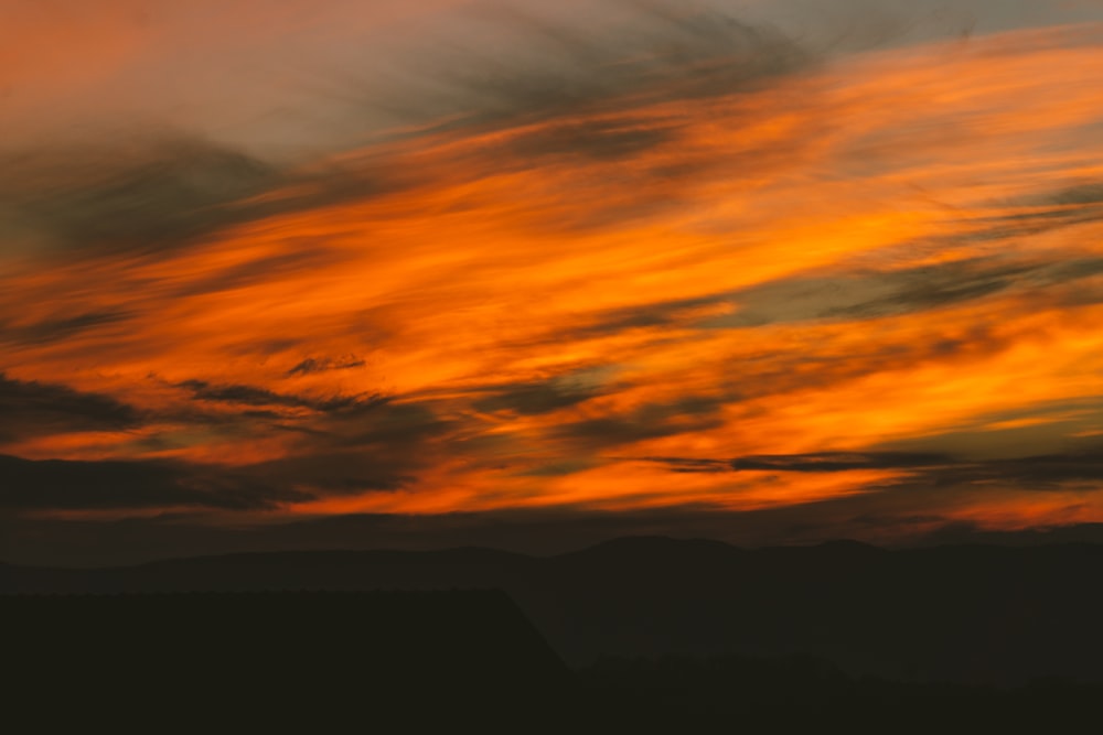 a plane flying in the sky at sunset