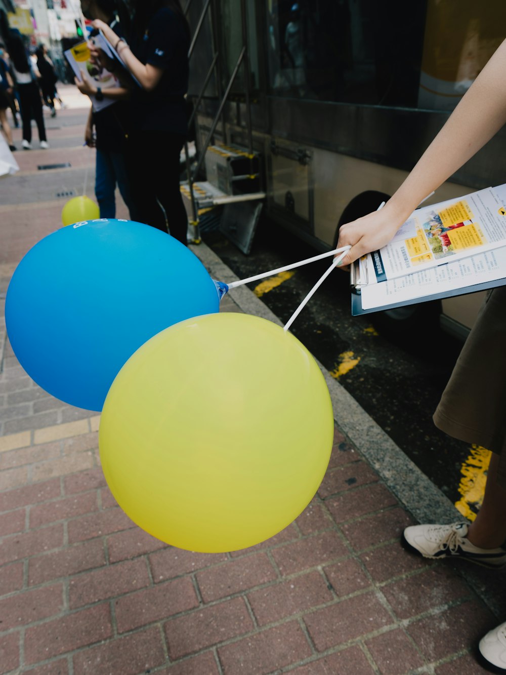 a person holding a bunch of balloons in front of a bus