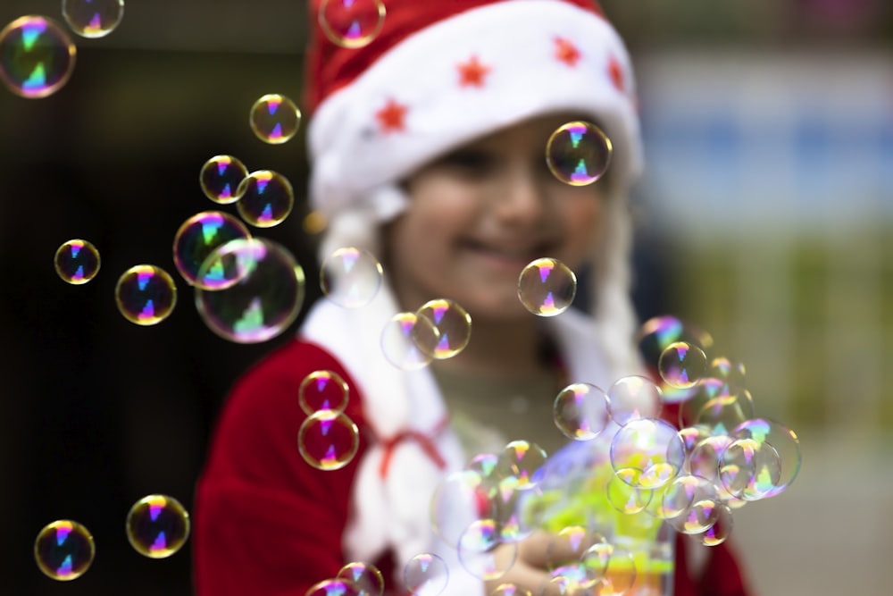 a little girl in a santa hat blowing bubbles