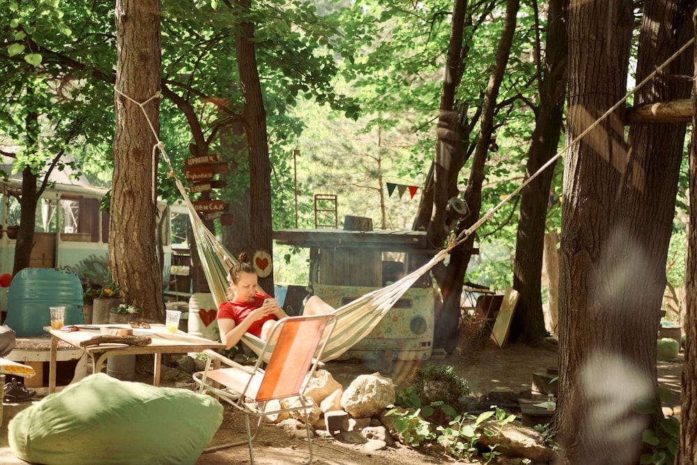 a woman sitting in a hammock in the woods