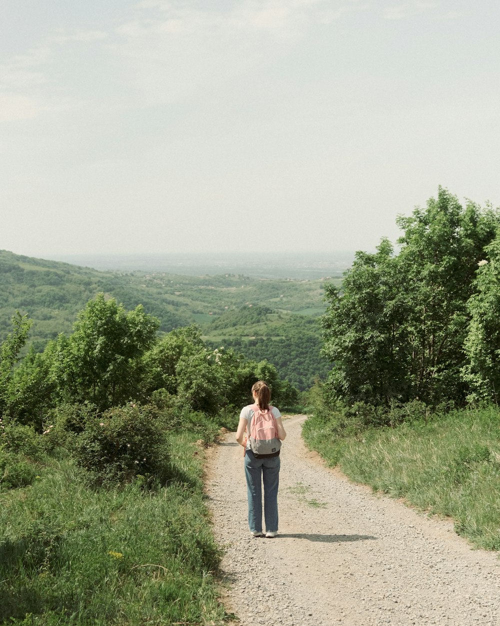 a woman is walking down a dirt road