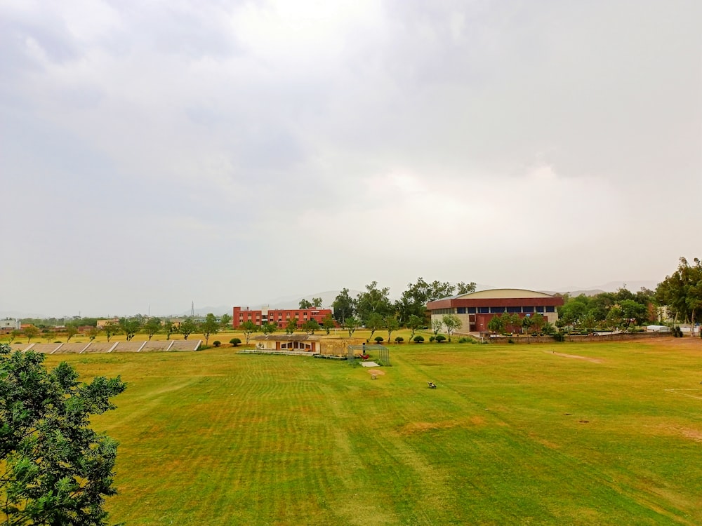 a large grassy field with a red building in the background