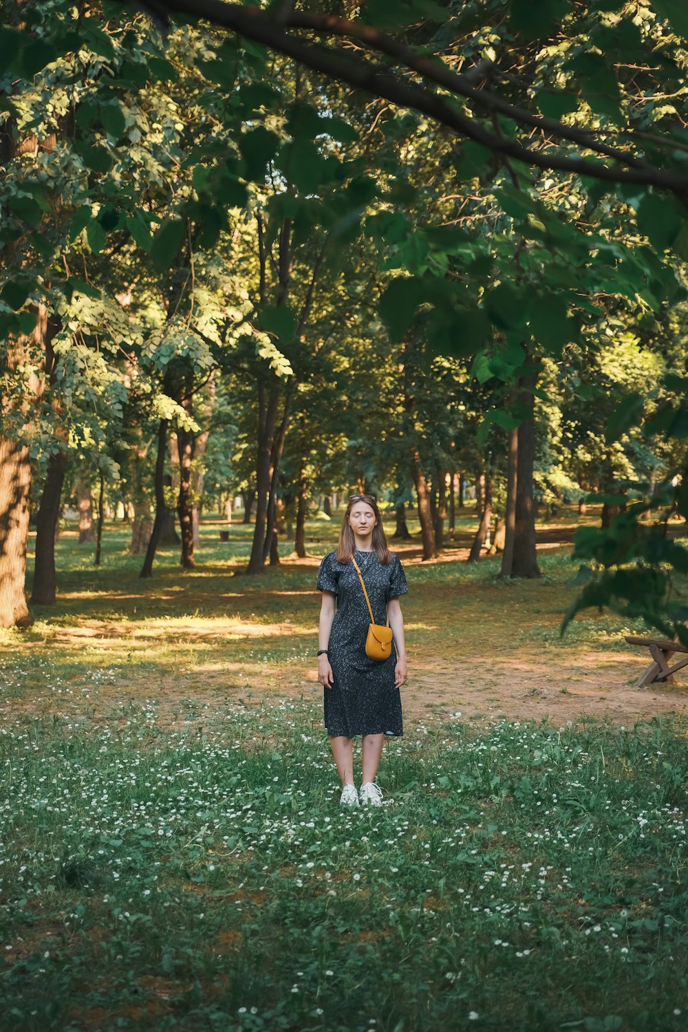 a woman standing in a field with trees in the background