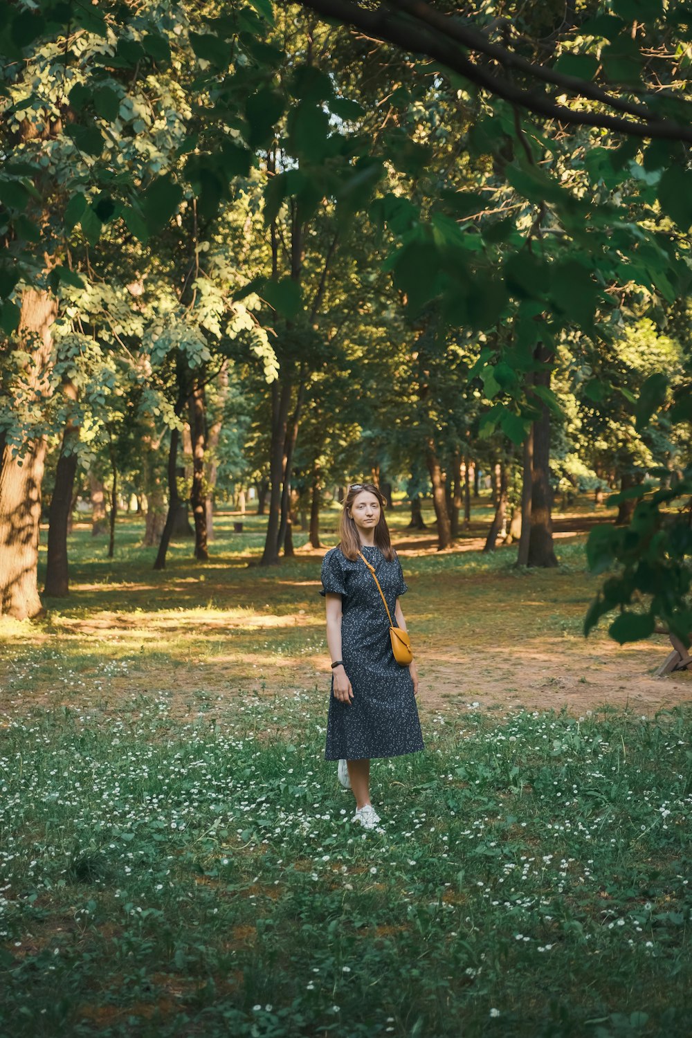 a woman standing in a field with trees in the background