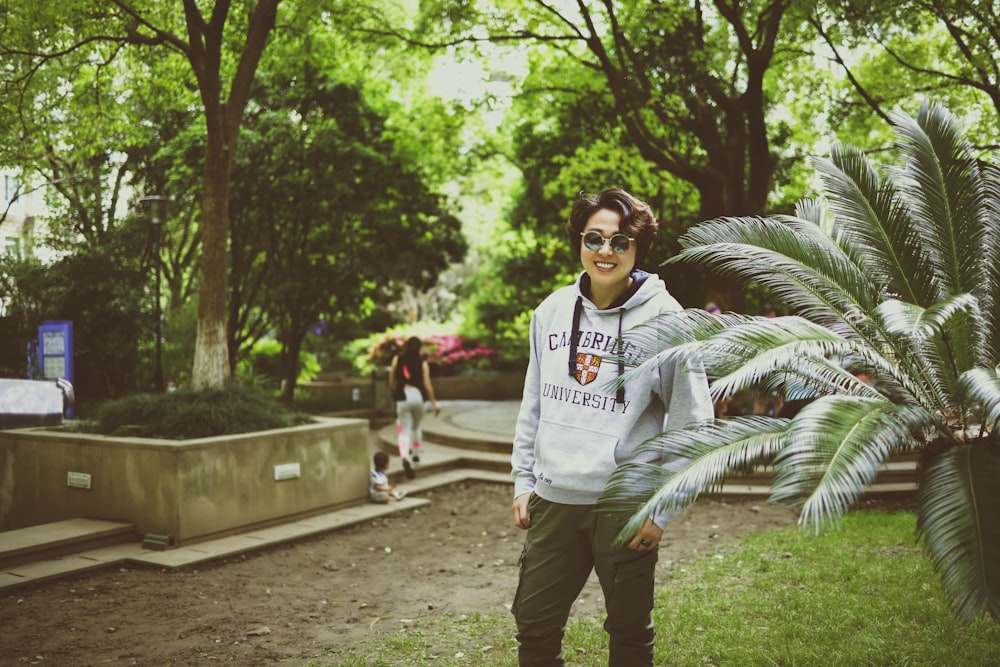 a woman standing in a park with a palm tree