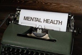 a close up of a typewriter with a paper that reads mental health