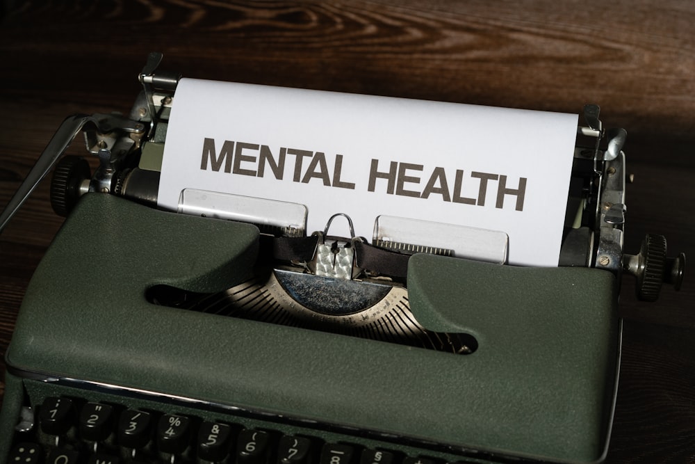 a close up of a typewriter with a paper that reads mental health