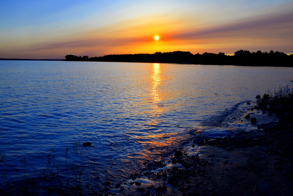 the sun is setting over a body of water