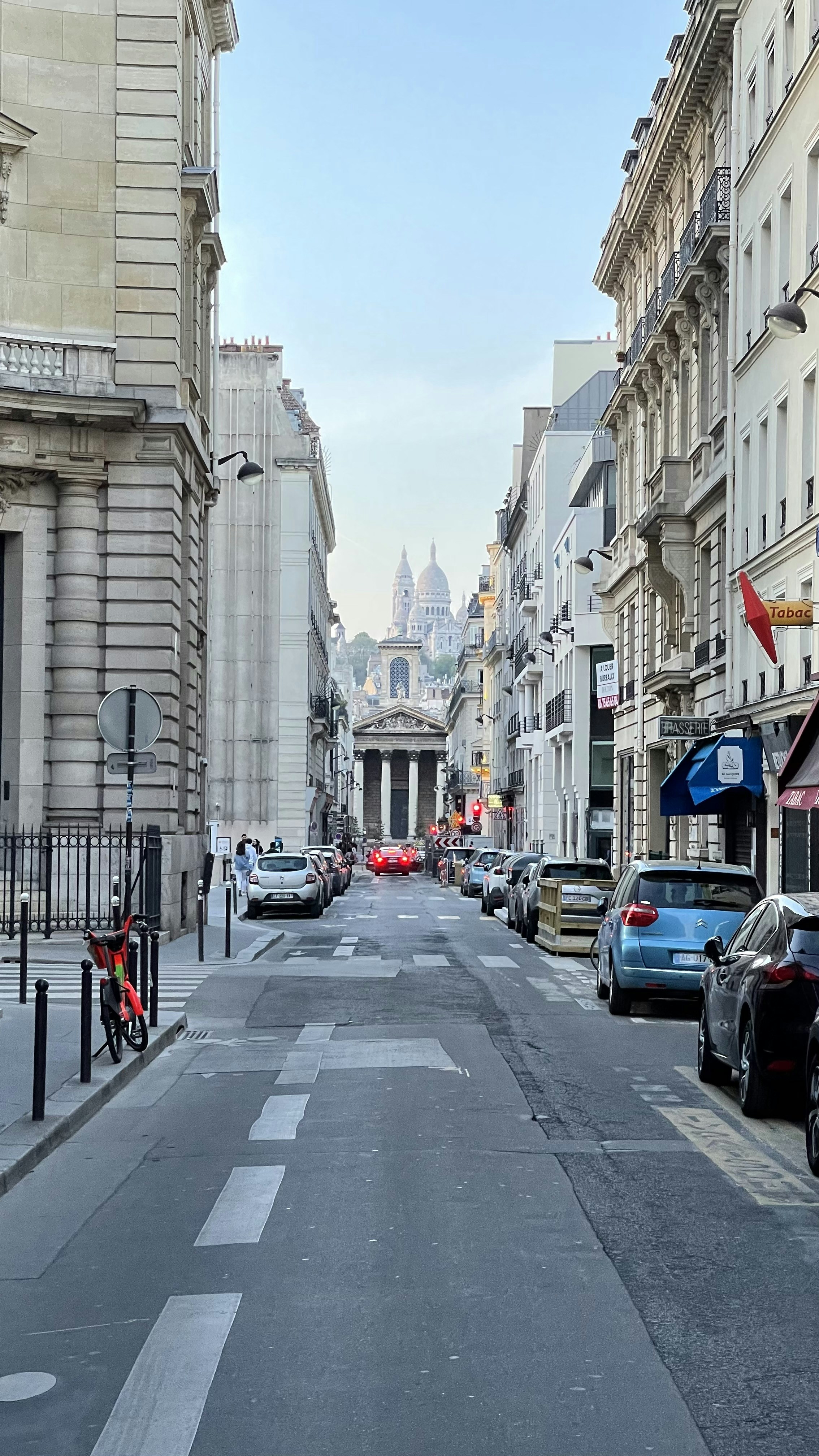 a city street lined with parked cars and tall buildings