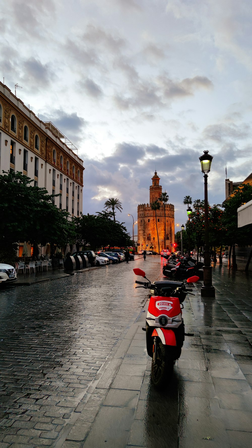 a red scooter parked on the side of a wet street