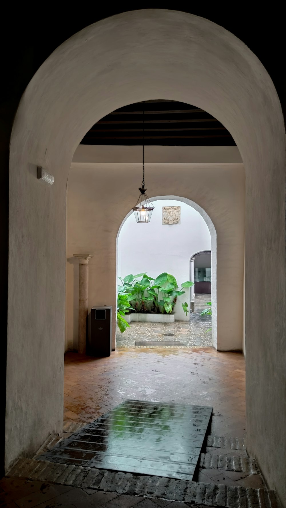 an archway leading into a courtyard with a potted plant