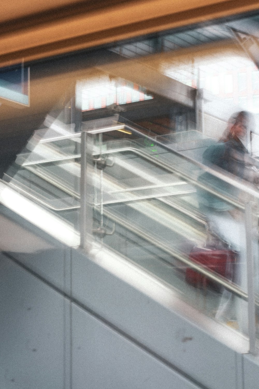 a blurry photo of a woman walking down an escalator