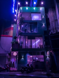 a building lit up at night with a motorcycle parked in front of it
