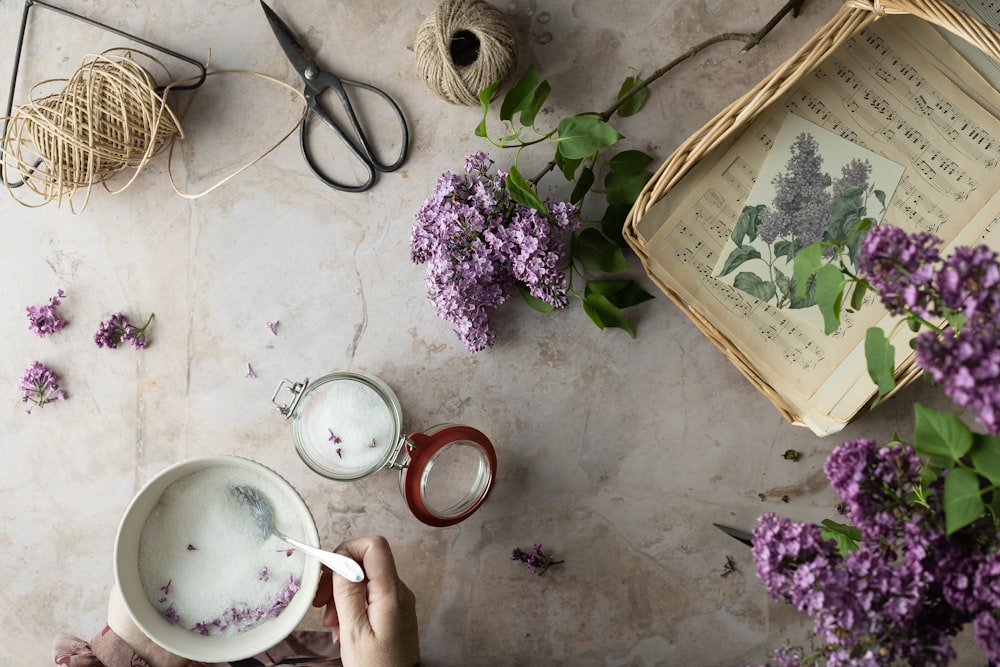 una persona che tiene una tazza di tè accanto ad alcuni fiori