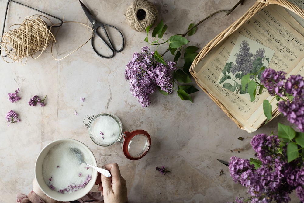 eine Person, die eine Tasse Tee neben ein paar Blumen hält