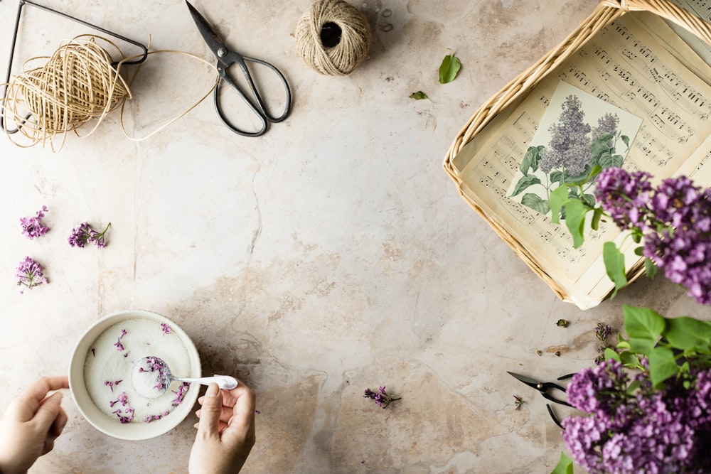 a person holding a cup of coffee next to some flowers