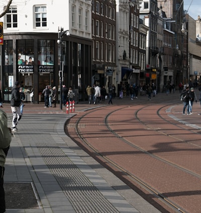 a group of people walking down a street next to tall buildings