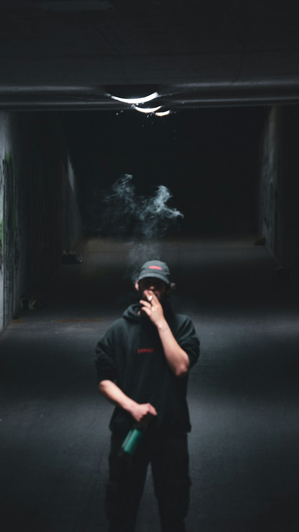 a man smoking a cigarette in a dark tunnel
