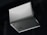 A silver laptop is shown upside down with its lid partially open, revealing the bottom side. The brand name 'Slimbook' is visible on the exterior, with rubber feet and ventilation details on the base. The background is dark, contrasting with the laptop's sleek metallic appearance.