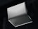 A silver laptop is shown upside down with its lid partially open, revealing the bottom side. The brand name 'Slimbook' is visible on the exterior, with rubber feet and ventilation details on the base. The background is dark, contrasting with the laptop's sleek metallic appearance.