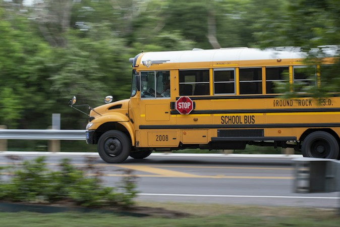 A yellow school bus driving down a road, a reminder that bus routes and travel time are part of any CCSD attendance boundary decision