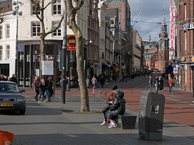 a group of people walking down a street next to tall buildings