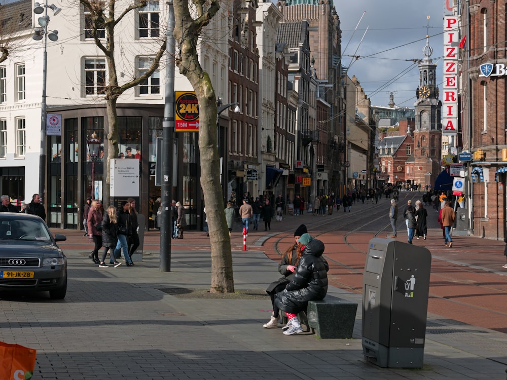 a group of people walking down a street next to tall buildings