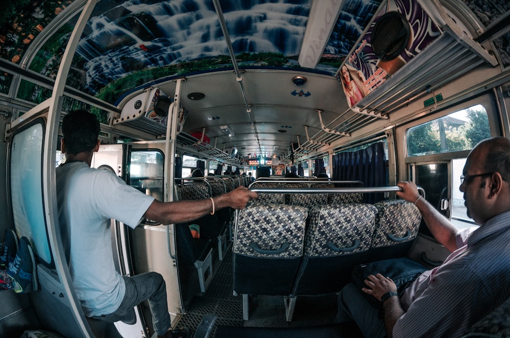 two men sitting on a bus looking at something