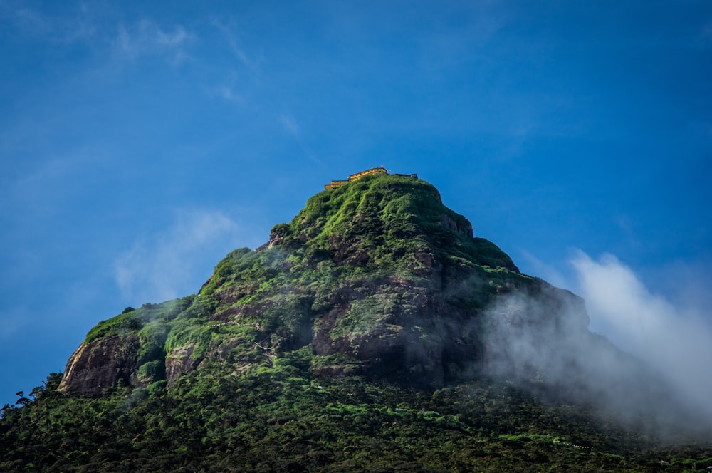 a very tall green mountain with a sky background