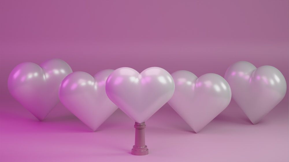 uma fileira de balões brancos em forma de coração em um fundo cor-de-rosa