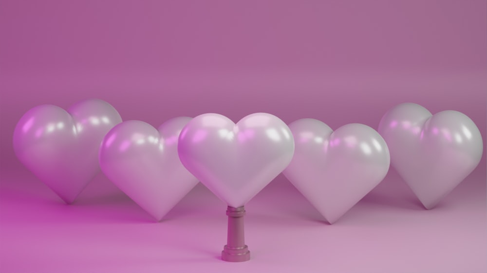 Una hilera de globos blancos en forma de corazón sobre un fondo rosa