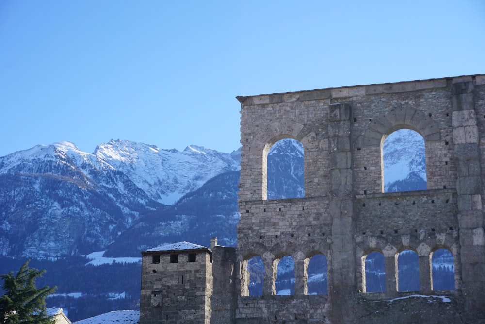 an old stone building with a mountain in the background