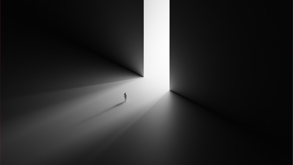 uma pessoa em pé em um quarto escuro com uma luz no final da sala