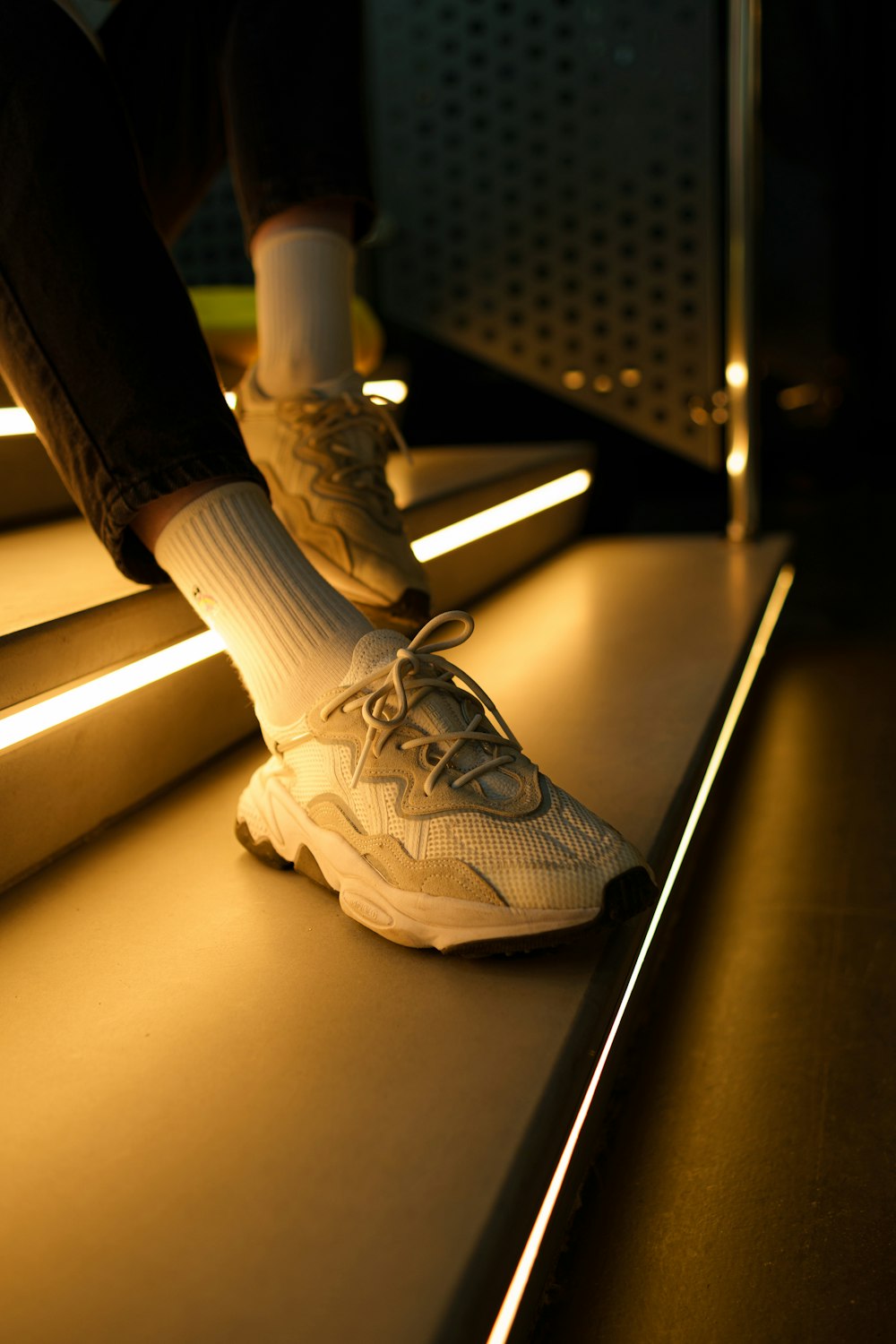 I piedi di una persona in scarpe da ginnastica bianche su una rampa di scale