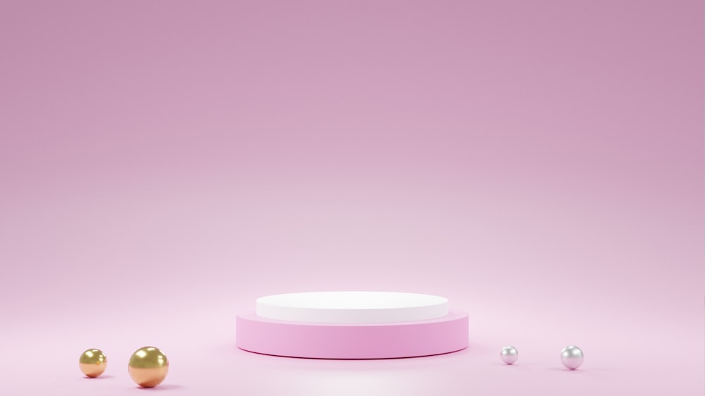 a pink and white container and three gold balls