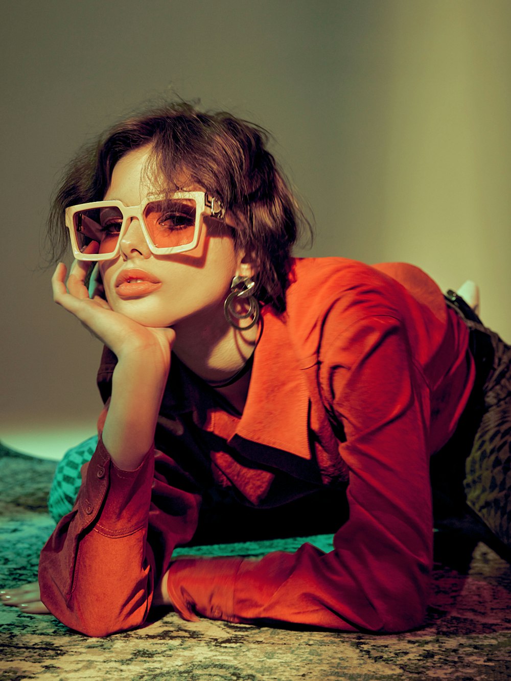 a woman wearing sunglasses laying on a bed