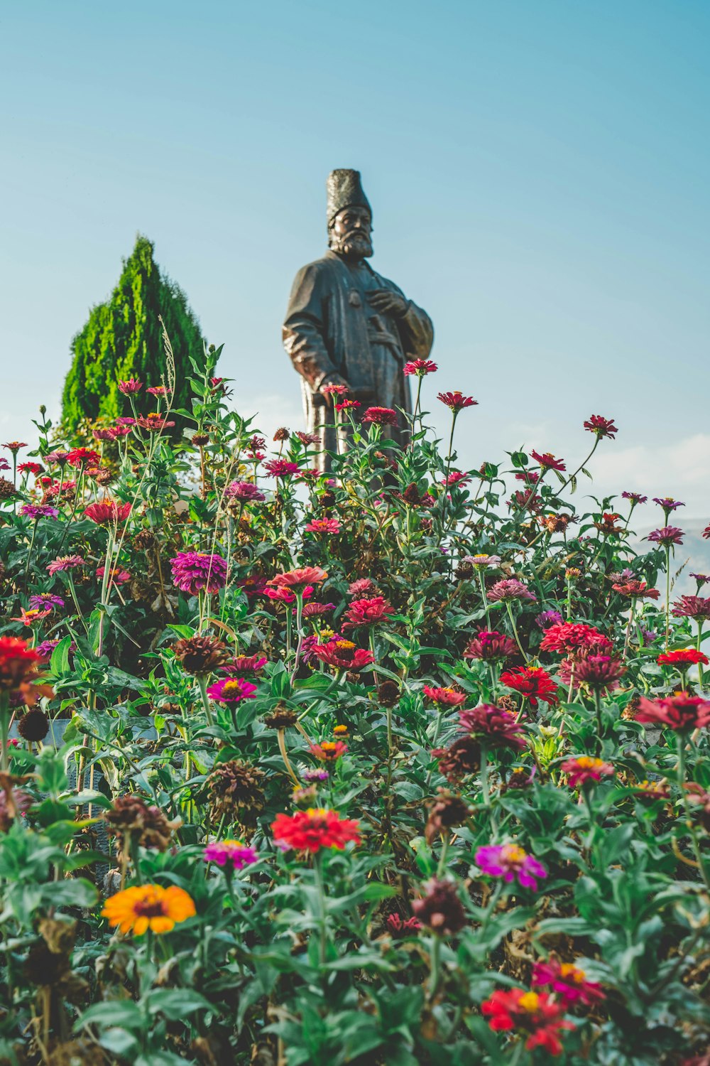 a statue in the middle of a field of flowers