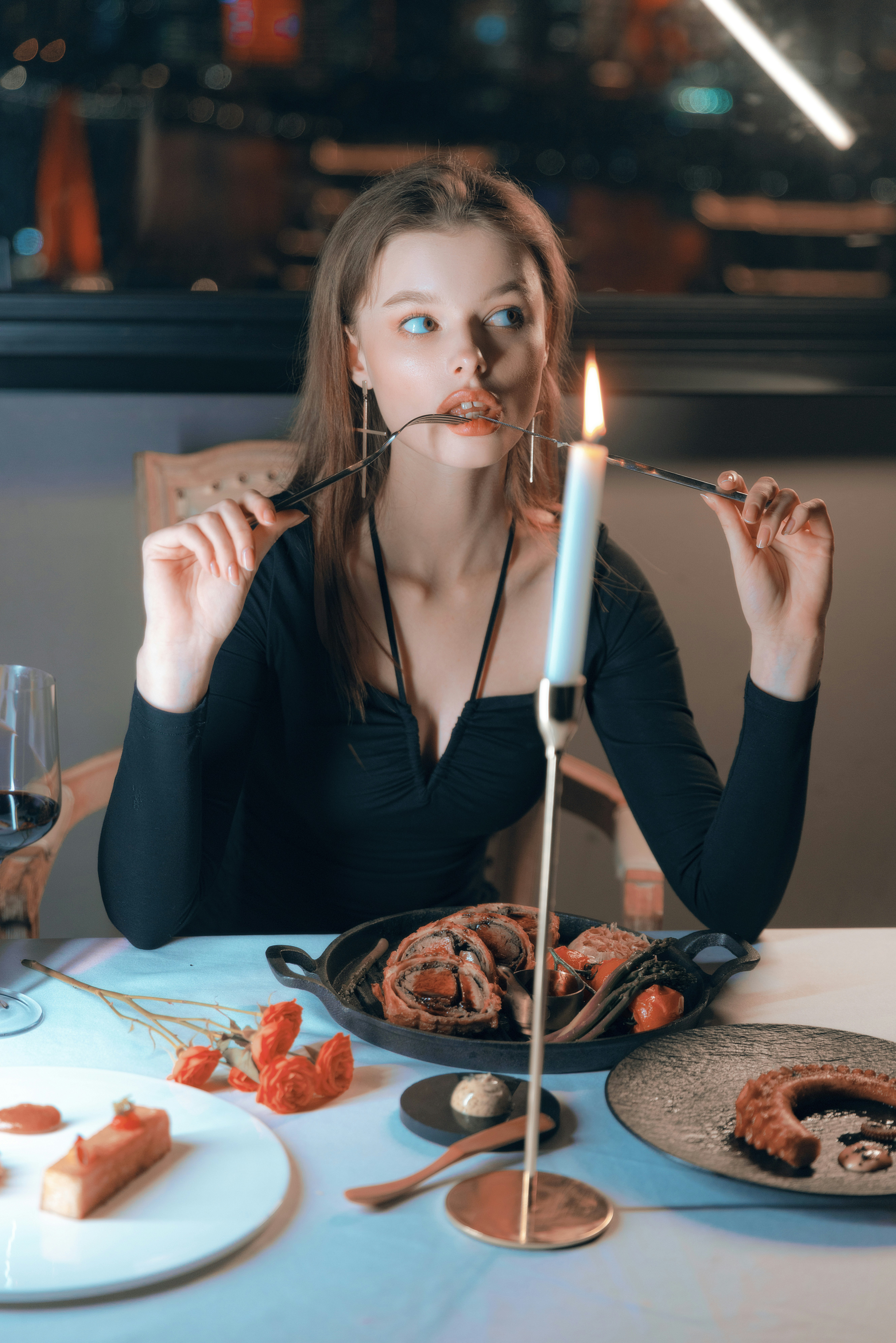 a woman sitting at a table with a candle in her mouth